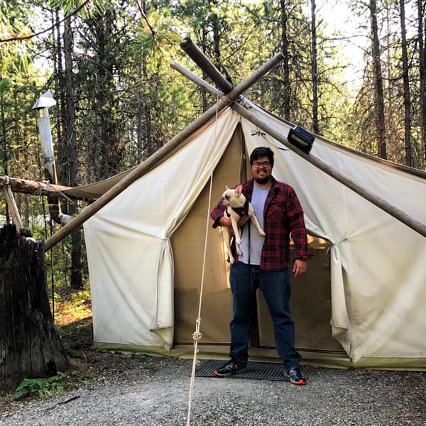 outside view standard tent Under Canvas Glamping Glacier National Park view of front of tent with man holding a dog