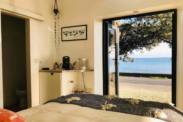 Glamping Belfast Brent Cove Waterfront Studio  view of the bed looking out to the sea across the road