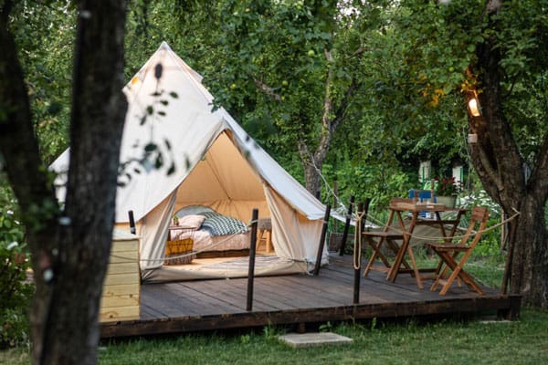 Dragonfly Gardens Glamping Tents Romania view of the tent on a deck with chairs and bed inside