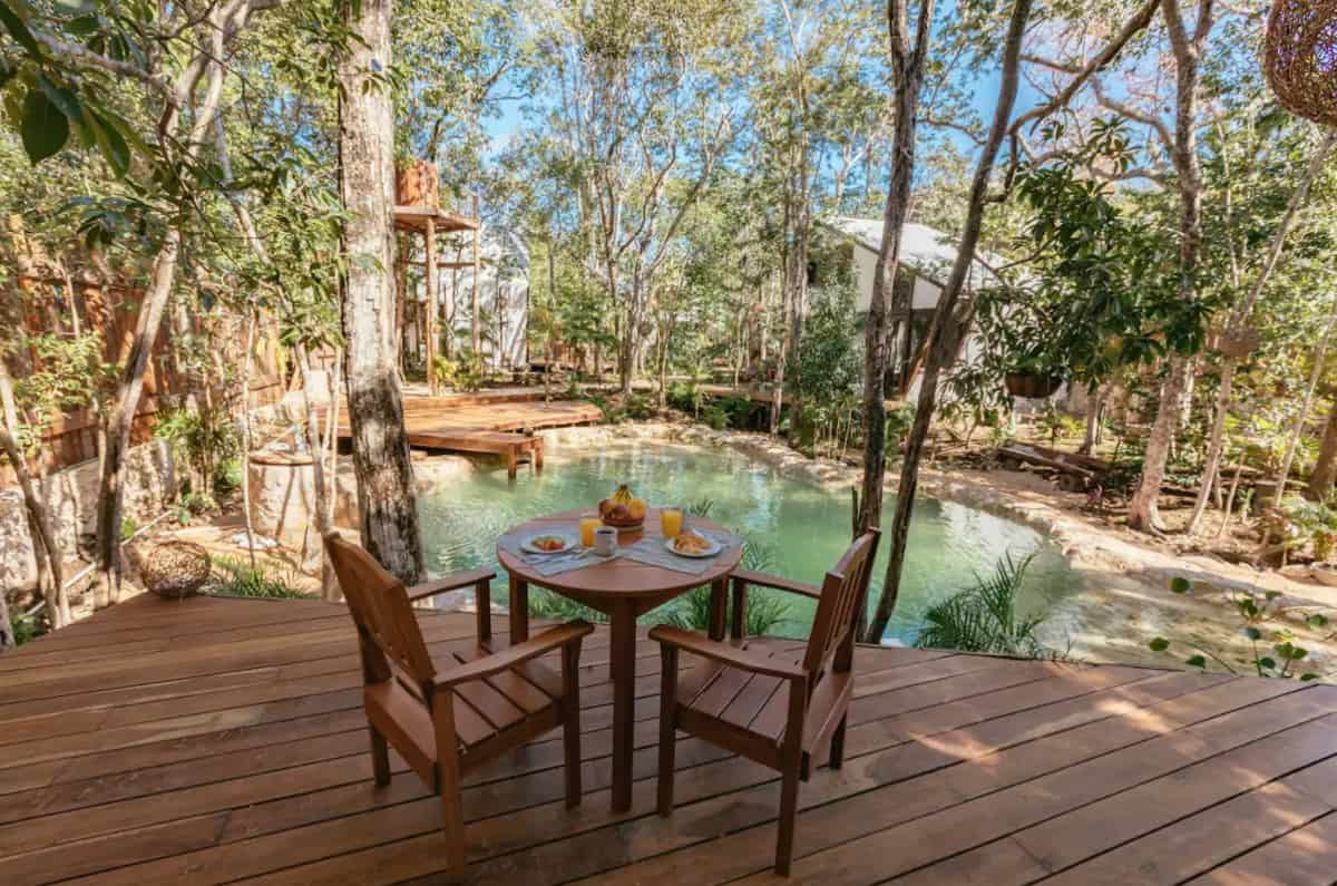 Chairs and table on a deck overlookign a cenote at Tulum glamping site