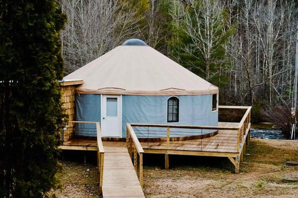 Brown Mountain Beach Resort Yurt rentals NC view of the front of the blue yurt with wrap around deck and river in the background