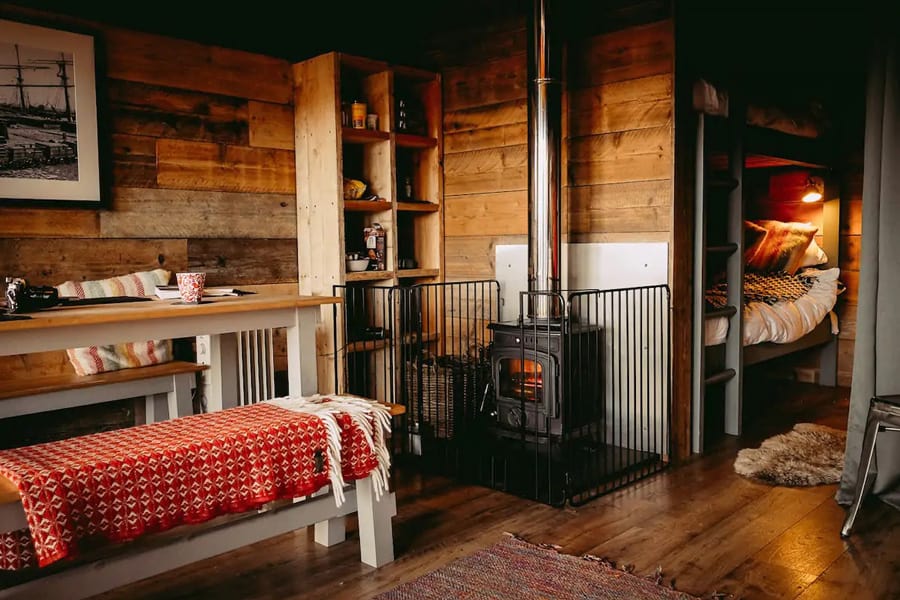 Llechwedd Glamping North Wales - Safari Tent view of inside of tent with bunk beds, stove and dining table