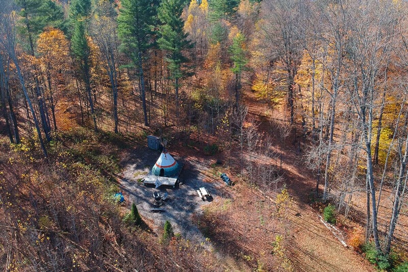 Cozy Vermont Tipi Retreat at Nwyfre Farm view from above with tipi, deck, picnic table and campfire among trees